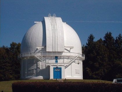 Photo of the exterior of a building with a blue door and white dome that is closed