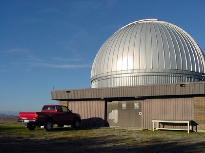 Photo of the exterior of a silver-coloured metal dome and a rectangular building with a red truck parked in front