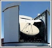 Exterior photo of a white, circular building with an open dome and a white telescope pointing towards the sky