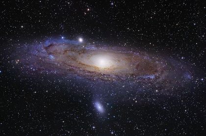 Photo of a central, luminous dot surrounded by scattered luminous dots and purple-tinged rings forming a large concentric disc in a star-filled sky against a black background