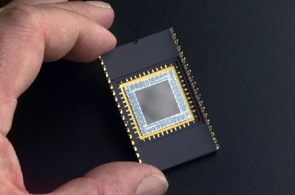 Photo of a hand holding a black rectangular device with a grey-coloured silicone square at its centre