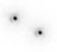 Two black dots surrounded by a darker halo at the centre that fades towards the exterior. The left dot is higher than the right dot.